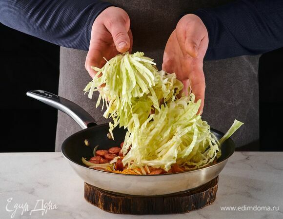 Добавьте капусту, накройте крышкой и томите на среднем огне, пока капуста не даст сок.