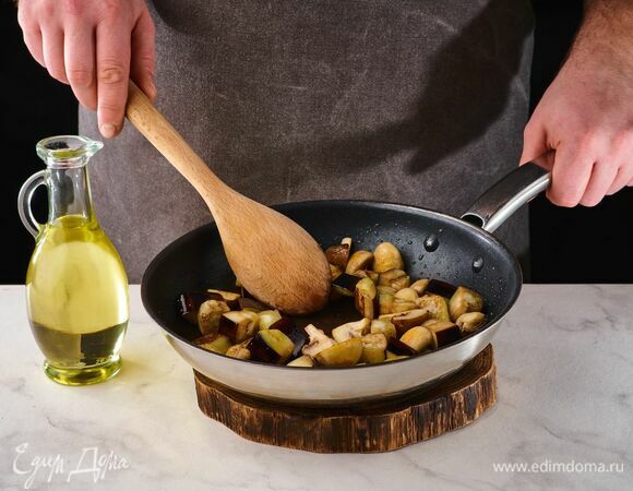 На сковороде в оливковом масле обжарьте шампиньоны. Готовьте на небольшом огне, помешивая, около 10 минут. При необходимости влейте немного воды. Добавьте нарезанные баклажаны и обжаривайте около 3 минут.
