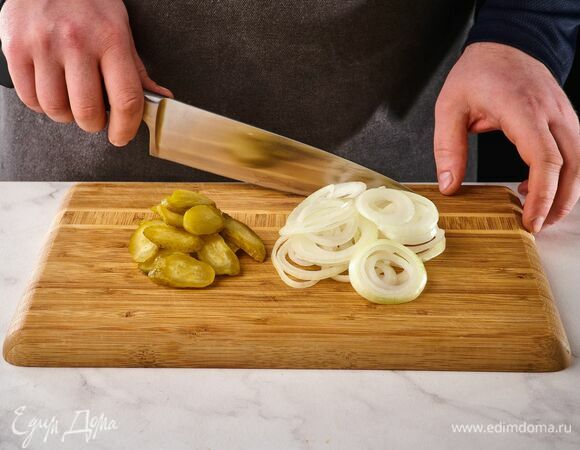 Лук почистите, нарежьте кольцами, маринованные огурцы нарежьте кружками.