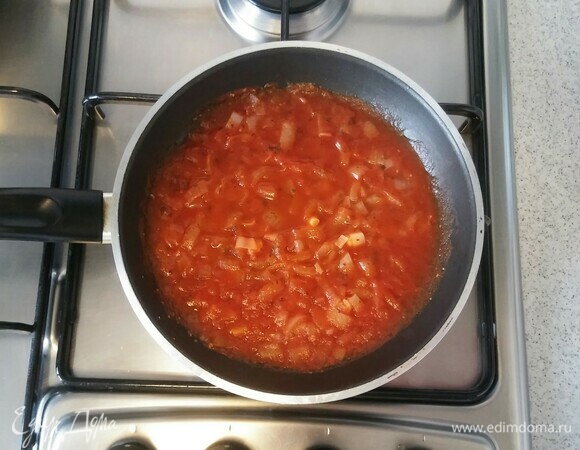 После этого для приготовления соуса нужно снова смазать сковороду сливочным маслом. Выложить измельченный репчатый лук, протертые помидоры и сушеный базилик. Перемешать. И на маленьком огне, помешивая, готовить соус к пицце около 10–15 минут (до мягкости лука).