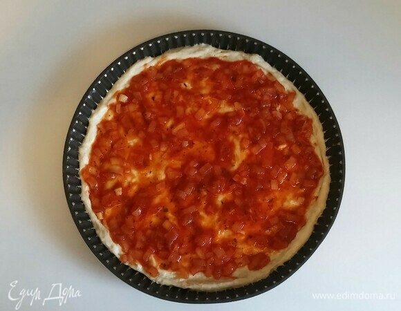 Противень для пиццы смазать оливковым маслом, чуть присыпать блинной мукой и раскатать тесто. Затем выложить на тесто томатный соус.
