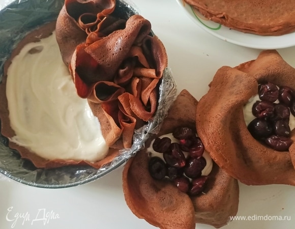 На дно формы выложить один или два блинчика. Сверху выложить немного крема. Затем взять другой блинчик, уложить его в небольшую чашечку, внутрь блинчика налить 2 столовые ложки крема, положить ягоды или фрукты, можно шоколад. Соединить края и положить в форму.