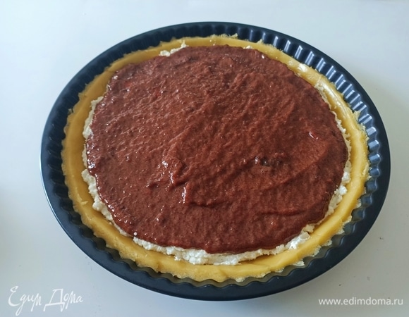 Форму смазать сливочным маслом. Тесто разделить на две неравные части. Большую часть теста раскатать в круг на 3 см больше диаметра формы. С помощью скалки аккуратно перенести тесто в форму. Плотно прижать ко дну и бортам. Убрать излишки теста и наколоть дно вилкой, чтобы тесто во время выпекания не поднималось. Затем выложить начинку — сначала рикотту, затем варенье.