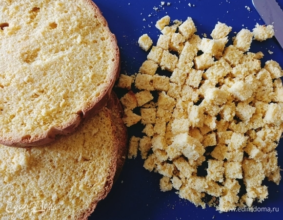 Бисквит разрезать на четыре одинаковых коржа. С одного срезать края и нарезать маленькими кубиками.