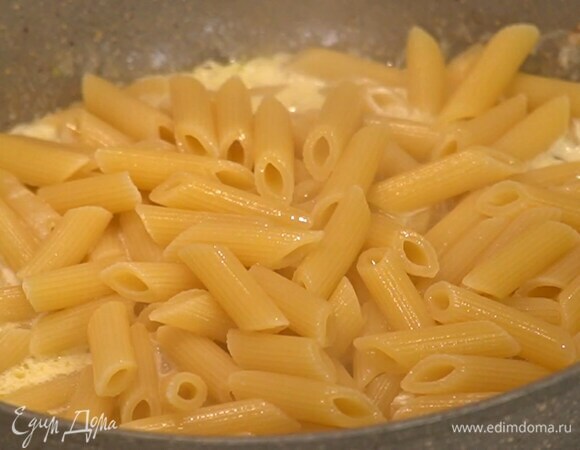 Пенне отваривать в подсоленной воде ровно половину времени, указанного на упаковке, затем воду слить и сохранить, макароны выложить в сковороду с луком и чесноком, все перемешать.