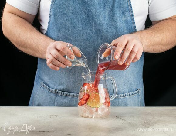 Выложите в кувшин лед, добавьте клубнику и лайм. Влейте клюквенный сок и сахарный сироп.