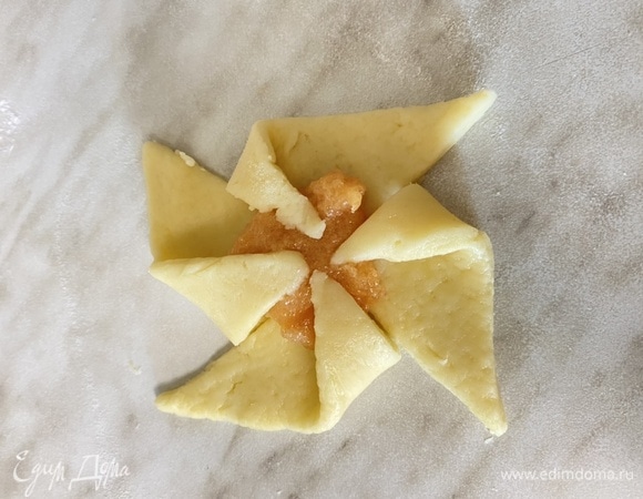 Поместите 1 чайную ложку джема в центр каждого квадрата. Острым ножом сделайте 3-х сантиметровые разрезы по диагонали от каждого угла к начинке. Сложите каждый второй кончик так, чтобы покрыть начинку, образуя вертушку. Слегка надавите, чтобы запечатать. Если тесто станет мягким, поставьте в холодильник до застывания.