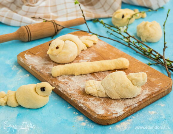 «Завяжите» жгут в узелок таким образом, чтобы один край смотрел вверх — это будет голова птицы, а другой вниз — это будет хвостик. Плотно узел не затягивайте. Чтобы придать птичке устойчивость, отрежьте от «хвоста» немного теста и снизу приклейте его к основанию булки.