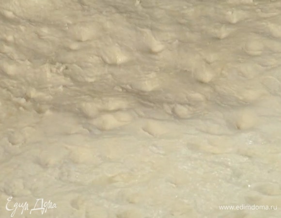 Противень сбрызнуть оставшимся оливковым маслом, выложить подошедшее тесто, равномерно распределить его по всей поверхности и пальцами сделать небольшие углубления.