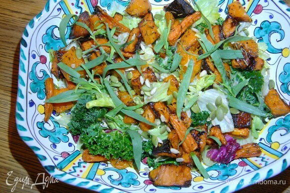 Посыпать салат семечками и листьями тархуна.