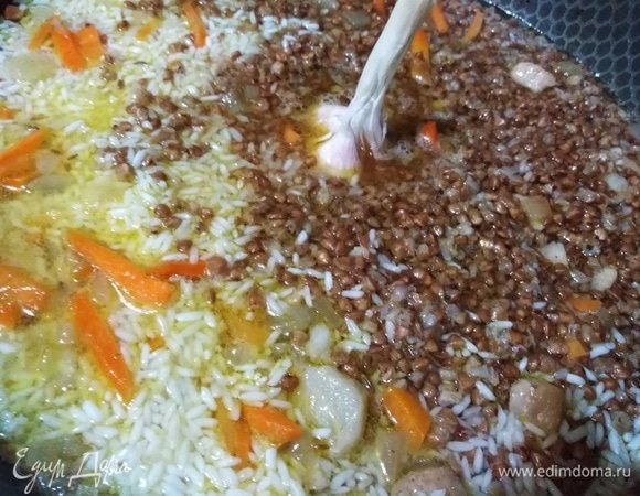 Когда вода выпарится до уровня крупы, добавить головку чеснока.