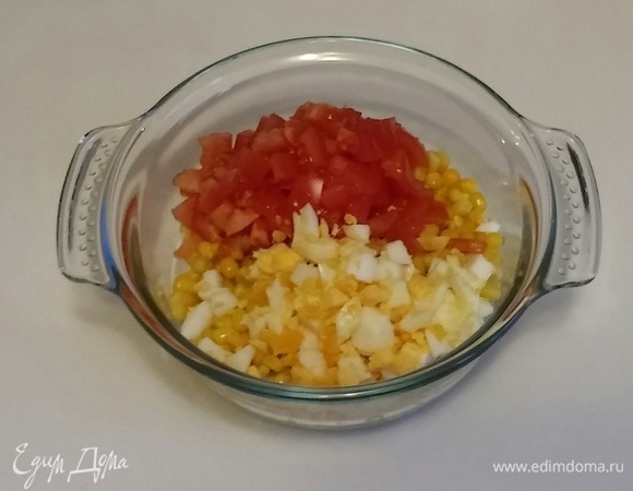 Отварить куриное яйцо вкрутую, охладить, почистить и нарезать мелкими кубиками. Помидор нарезать так же, как куриное яйцо. Затем выложить все в емкость к кукурузе.