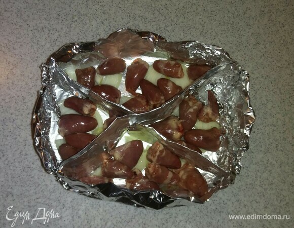 Затем поверх репчатого лука выложить часть куриных сердечек. Посолить.