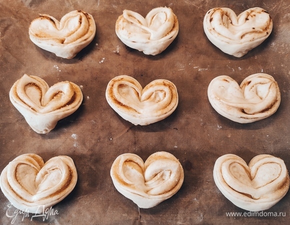 Смешать корицу, сахар и цедру одного апельсина, растопить сливочное масло. Каждый шарик раскатать в овал, смазать сливочным маслом, посыпать смесью корицы, сахара и цедры. Скатать овал в рулет, соединить концы рулета, защипнуть, сделать надрез и развернуть рулет. Накрыть плюшки полотенцем и оставить на 15 минут, чтобы поднялись.