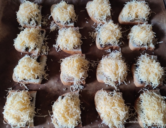 Сыр натереть на мелкой терке и посыпать сверху шпрот. Поставить бутерброды запекаться на 7 минут при температуре 200°C.