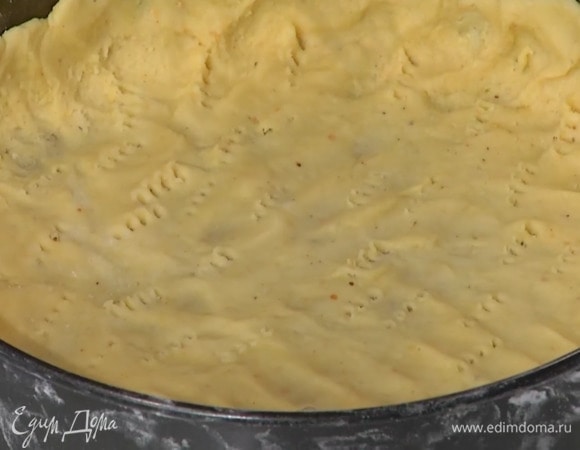 Дно формы диаметром 26 см выстелить бумагой для выпечки, выложить тесто и сформировать тонкий корж с бортиками, часто наколоть его вилкой, накрыть бумагой для выпечки и всыпать бобовые.