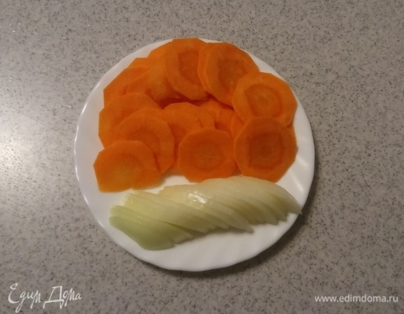 Пока куриные сердечки маринуются, нужно подготовить овощи для луково-морковной подложки. Для этого репчатый лук нарезать дольками, а морковь — тонкими кружочками (толщина кружочка — 1 мм).