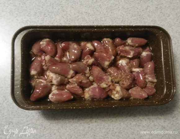 Затем поверх слоя репчатого лука выложить слой замаринованных куриных сердечек вместе с маринадом.
