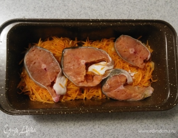 Рыбу (я использовала стейки горбуши) предварительно натереть солью и свежемолотым черным перцем, выложить в форму на слой моркови и репчатого лука. Затем поставить форму в разогретую до 190°C духовку на 40 минут. При подаче украсить зеленью укропа. Приятного аппетита!