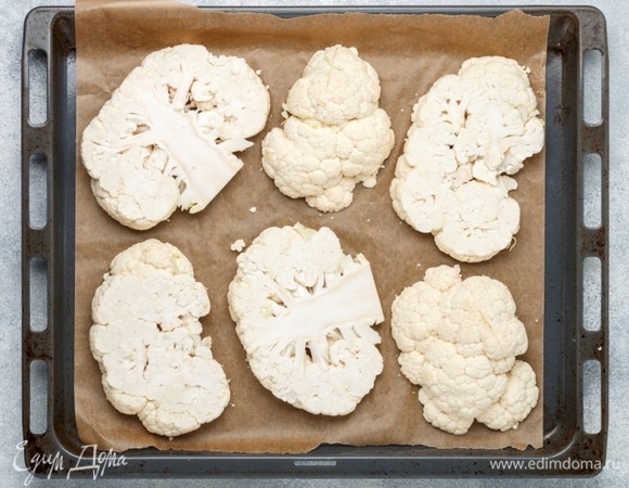 Кочан цветной капусты нарезать стейками толщиной 1,5–2 см. Противень застелить пергаментом.