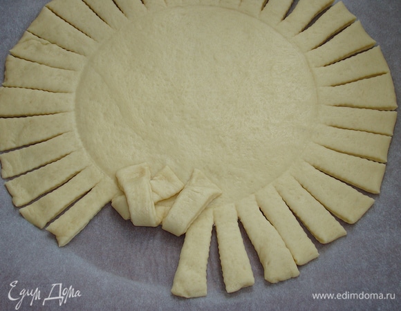 Начинаем плести бортик ватрушки. Одну полоску заверните в середину — в правую сторону, вторую полоску в левую, перекрывая предыдущую.