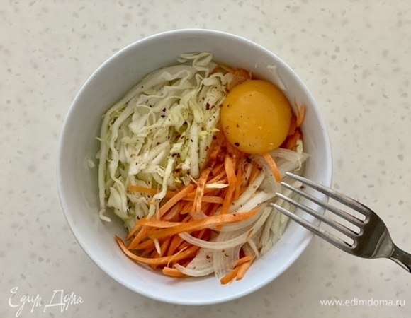 Капусту, репчатый и зеленый лук, морковь нашинковать тонкой соломкой, сложить в миску, залить яйцом, приправить солью и перцем, перемешать.