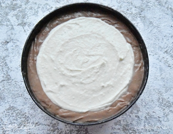 Форму для выпекания застелить пергаментом, смазать его небольшим количеством растопленного сливочного масла. Распределить по форме подготовленное шоколадное тесто, затем выложить творожную массу, не доходя до краев шоколадного теста 1–1,5 см. Поместить форму с тестом в холодную духовку. Включить ее на 180°C и выпекать пирог около часа. В данном рецепте использую форму диаметром 18 см.<br />
Летом обязательно подайте к шоколадной ватрушке ягодный соус. Идеально подойдет вишня. Для соуса проварите 200 граммов ягод с небольшим количеством сахара. Для густой консистенции ягодного соуса добавьте 1 ст. л. крахмала, размешанного в 0,5 стакана воды.