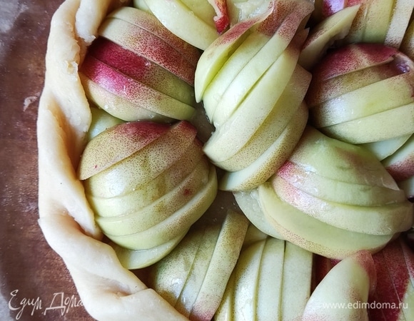 На середину теста выложите сахар, предварительно смешанный с крахмалом (делаем это для того, чтобы сок, который выделяется из фруктов, не вытек). Выложите нарезанные фрукты, соберите края и смажьте их желтком, смешанным с куркумой. Затем выпекайте при 180°C (режим «Верх/низ») примерно 20–25 минут.