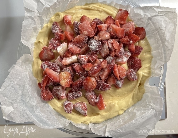 Клубнику перемешайте с одной столовой ложкой крахмала или муки. Тесто поместите в подготовленную форму, сверху выложите клубнику.