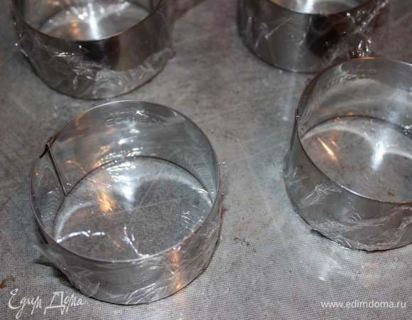 Подготовьте кондитерские круги для крема. Для этого натяните пищевую пленку на донышки.