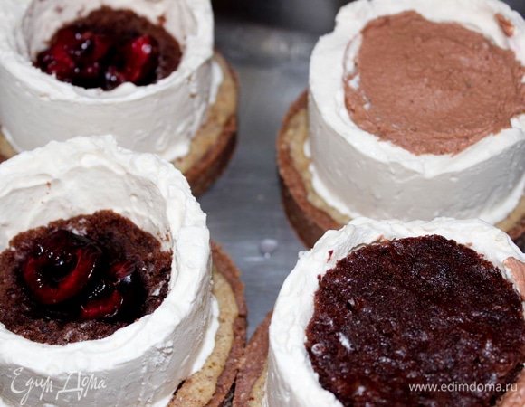 Начните заполнять колодцы из крема. Положите на дно кружок женуаза, затем вишню, покройте ганашем и положите сверху еще один кружок женуаза. Затем выньте колодец из кондитерского кольца, переверните и выложите на тарталетки. Уберите в морозилку минут на 15.