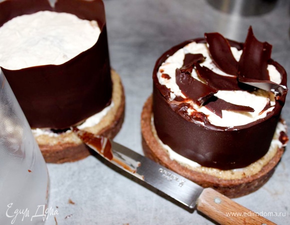 Аккуратно отклейте пергамент. Затем горячим ножом (можно нагреть на газе или в горячей воде, тогда лезвие надо обязательно вытереть) аккуратно срежьте излишки шоколада над пирожным. Используйте их для украшения.