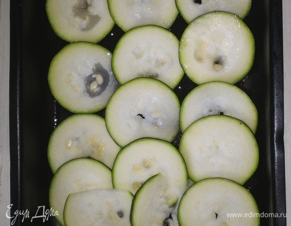 Форму для запекания смазать растительным маслом. Выложить половину кружков цукини в форму с небольшим нахлестом. Немного посолить.