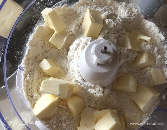 Приготовить песочное тесто для основы. Тут есть несколько важных моментов. Первое — все ингредиенты должны быть очень холодными — масло из холодильника, вода ледяная. Второе — никакого долгого замеса. Масло в тесте не должно плавиться и таять, иначе песочное тесто после выпечки будет не рассыпчатым, а дубовым. И последнее — масло брать исключительно качественное, 82,5% жирности. Смешать муку с солью и сахаром и переложить в чашу блендера (с ножами-измельчителями, не погружной).