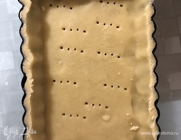 Охлажденное тесто разделить пополам и каждую часть раскатать в длинный прямоугольник толщиной 3 мм. Уложить в форму, прижать ко дну и бортикам, формируя основу, наколоть вилкой. Повторюсь, все необходимо делать быстро.