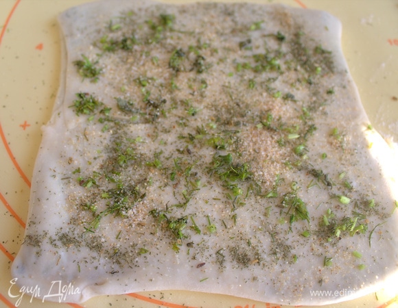 Снова сложите тесто к центру, но уже с другой стороны. Посыпьте зеленью и специями.