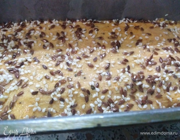 Дайте тесту подняться, после чего смажьте верх водой и посыпьте семенами.