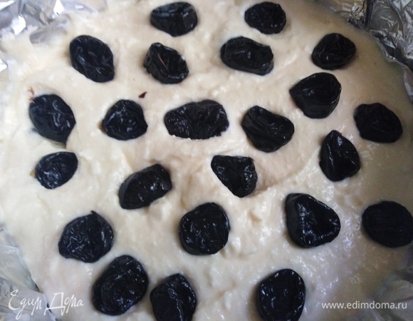 Половину массы выложить на тесто. Сверху выложить чернослив.