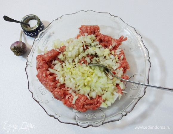 Добавить в мясной фарш измельченные луковицу и чеснок, соль и перец. Тщательно перемешать.