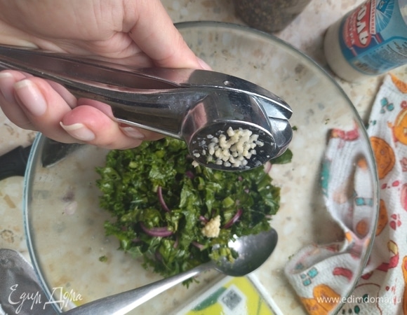 Измельчить зубчик чеснока с помощью чеснокодавилки и добавить к салату.