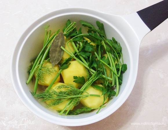 Для этого блюда картофель необходимо отварить до готовности. При жарке он теряет влагу, а при варке впитывает в себя все ароматы добавленных в воду специй и трав. Будем варить картофель с лавровым листом, черным перцем горошком. Добавьте в емкость жесткие стебли петрушки и укропа, а более мягкие части зелени оставьте для приготовления ароматного масла.