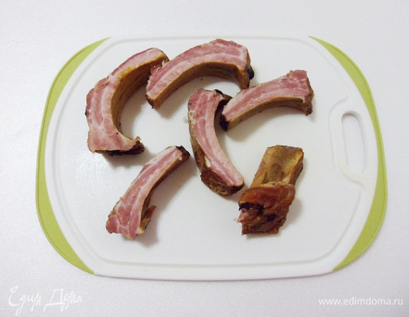 Копченые ребра режем по косточкам. В кастрюлю вливаем кипяток, учитывая, что еще будет добавлена капуста, выкладываем ребрышки и варим еще около 5 минут. Картошка должна свариться до полуготовности.