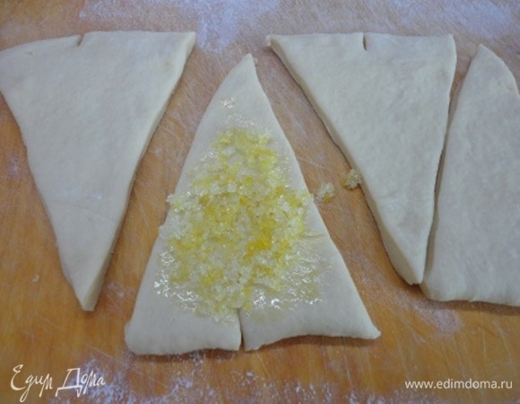 Тесто разделите на несколько частей и каждую раскатайте в прямоугольник. Затем разрежьте на треугольники. На основании каждого треугольника сделайте надрез, чтобы круассан при формовке приобрел дугообразную форму. Выложите начинку.