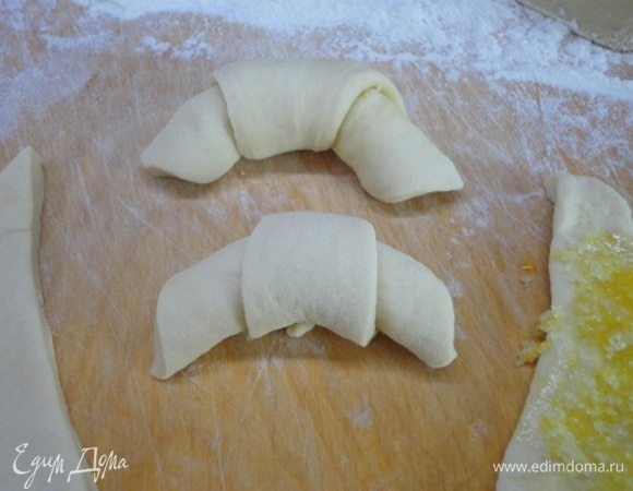 Сверните треугольники в круассаны, выложите на противень и дайте расстояться 20–30 минут. Выпекайте при температуре 180°C 20–25 минут.