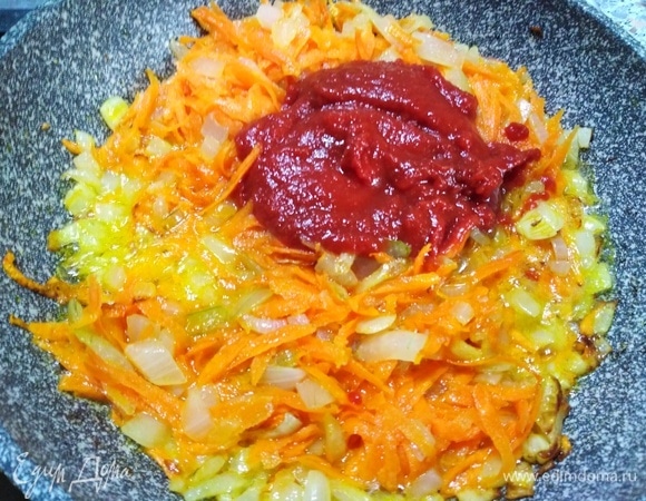 Обжарьте вторую головку лука с остатками моркови. Добавьте томатную пасту и сахар. 