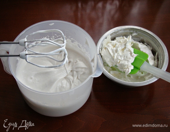 Затем продолжите взбивать белки, одновременно вливая тонкой струйкой горячий сироп. После того как сироп будет влит, частями добавьте крем из сливочного масла и сгущенного молока.