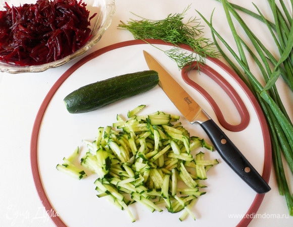 Промойте холодной водой зеленый лук, укроп и огурцы. Огурцы измельчите тоненькой соломкой. Свеклу натрите на крупной терке.