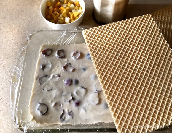 Прямоугольную форму застелите пищевой пленкой. Выложите вафельный пласт (26х18), сверху залейте массой с персиками, затем уложите второй пласт, массу с черешней и сверху — третий вафельный корж. Накройте пищевой пленкой и поместите в морозильную камеру до застывания.