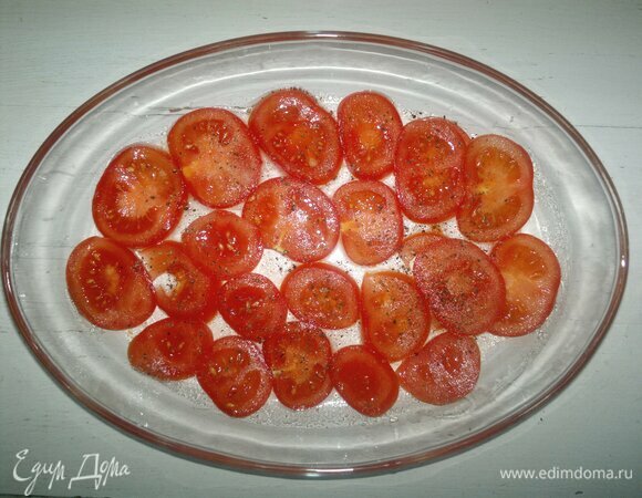 Форму для запекания смажьте оставшимся растительным маслом. Выложите на дно часть помидоров, немного посолите и поперчите.