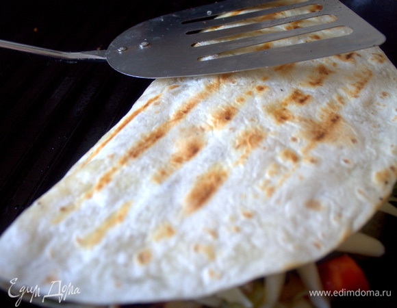 Накройте половинкой тортильи начинку, прижмите лопаткой и обжарьте.